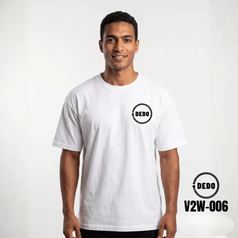 Rear view of a man standing under a stone archway, wearing a white oversized t-shirt featuring a black futuristic cybernetic circuit board skull print on the back. The DEDO logo and product code V2W-006 are displayed in the bottom-left corner.